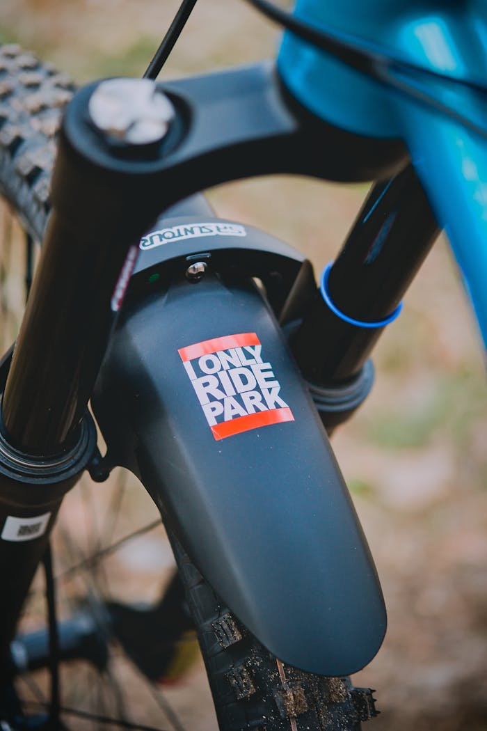 Detailed close-up of a mountain bikes front mud guard with a sticker, showcasing outdoor adventure gear.